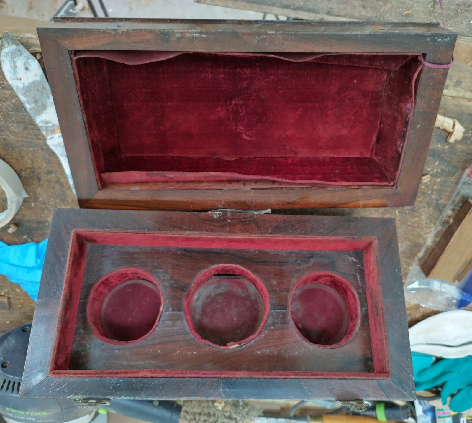 Image 1: rosewood caddy open on the bench before treatment, showing water damaged silk linings
